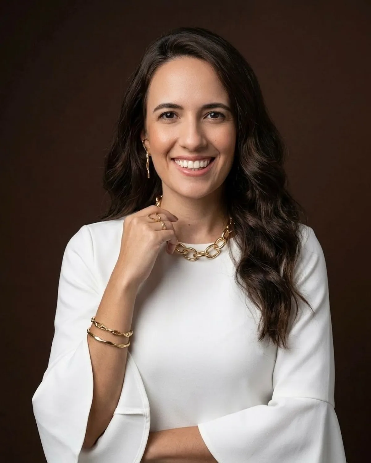 Vanessa Bento, consultora de imagem e estilo, de blusa branca sobre fundo marrom